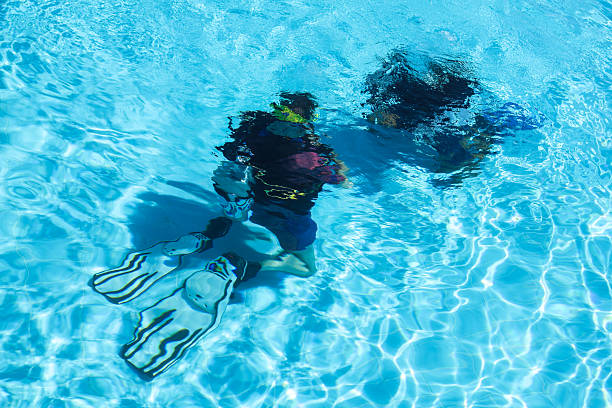 A diving instructor teaches a person underwater in a swimming pool.
