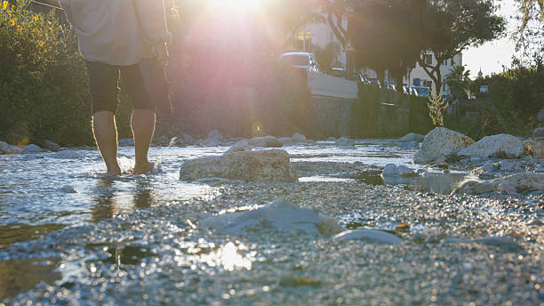 Low angle view of man walking in stream at sunrise, Finale Ligure