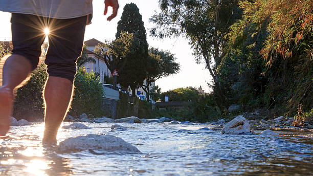 Low angle view of man walking in stream at sunrise, Finale Ligure