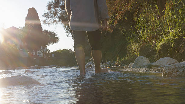 istock Low angle view of man walking in stream at sunrise 2250087047