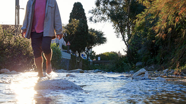 Low angle view of man walking in stream at sunrise, Finale Ligure