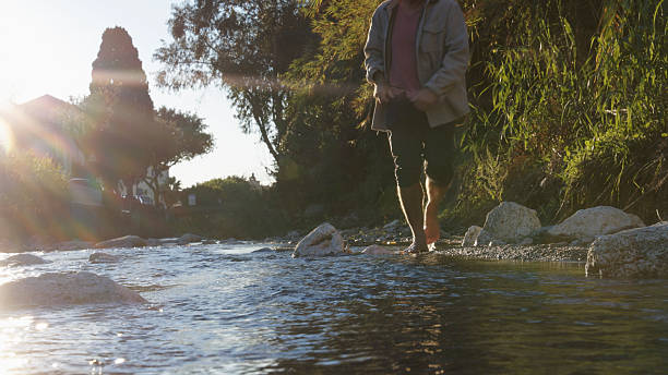 istock Low angle view of man walking in stream at sunrise 2250087060