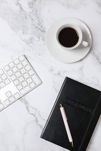 istock Top view vertical of coffee cup, white keyboard and black notebook on marble background, clean minimalist workspace style. Concept of modern workspace and creative lifestyle 2250088805
