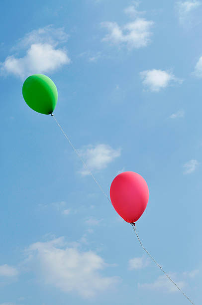 red and green ballons tied together flying in the sky