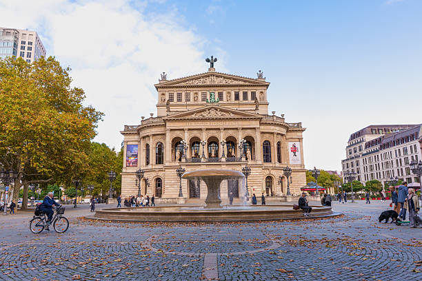 Frankfurt, Germany - October 21, 2025: Iconic Alte Oper, a magnificent opera house, stands prominently in Frankfurt's urban landscape during a vibrant autumn day, surrounded by people and a fountain.