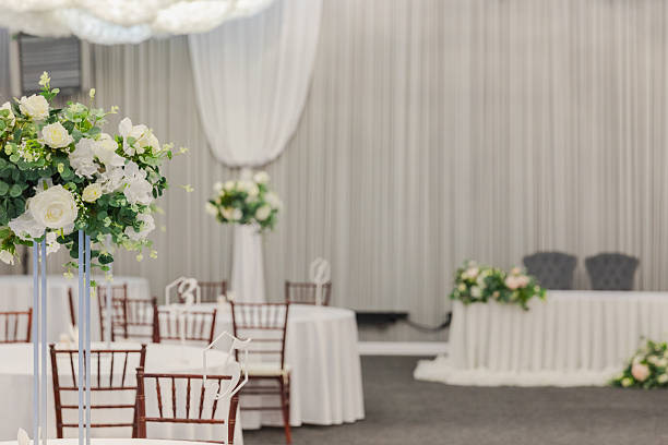 istock Decorated interior for festive event. Fancy table set for dinner with white flower composition in restaurant, luxury interior background. Wedding elegant banquet decoration arranged by catering service. 2250096523