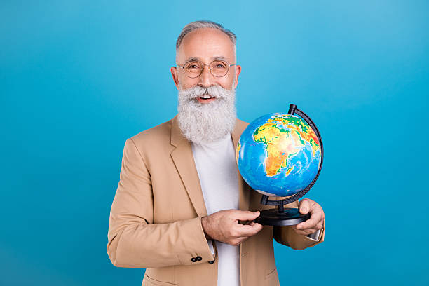 istock Portrait of handsome cheerful grey-haired man holding globe knowledge tutor isolated over bright blue color background 2250102637