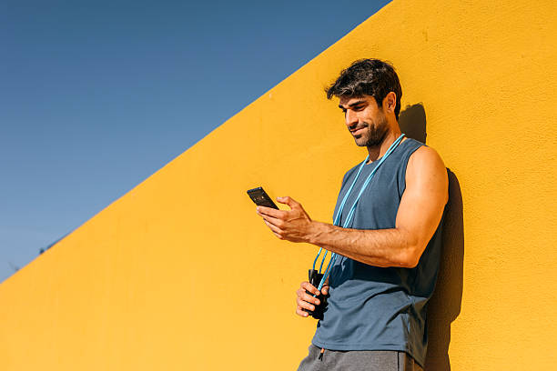 istock Portrait of a young man leaning on a wall using a smartphone 2250104098