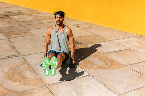 Fit man performing an exercise on push-up equipment outdoors, keeping his legs straight and hands on the bars, demonstrating strength, core engagement, and an active fitness routin