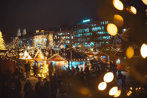 Zurich HB, Switzerland, December 5 2025. Sechselautenplatz Christmas market at night. People visiting the stalls and shots, above point of view, bokeh ball highlights in the foreground