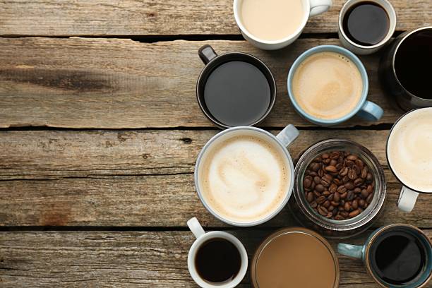 istock Different coffee drinks in cups and beans on wooden table, flat lay. Space for text 2250110424
