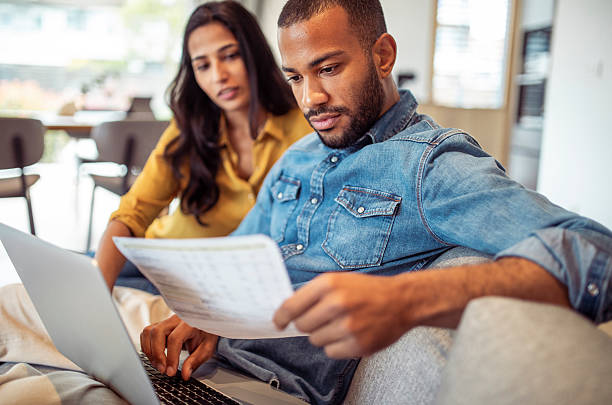 istock Engaged Couple Reviewing Financial Documents on Sofa Together 2250112482
