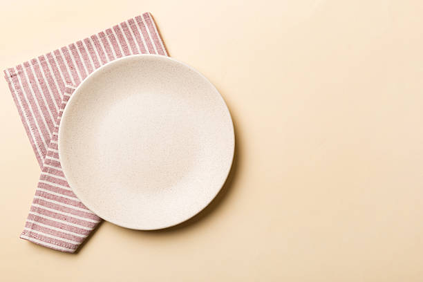 istock Top view on colored background empty round white plate on tablecloth for food. Empty dish on napkin with space for your design 2250114689