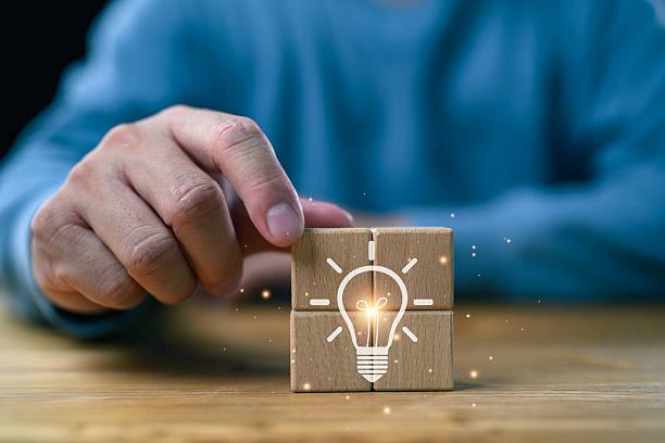 istock Brainstorming creative idea and innovation. Hand putting over wooden cube block with light bulb icon, having an idea symbolized by icons on cubes. Ideas and innovation concept. 2250119903