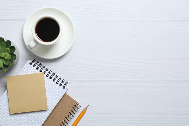 istock Office table with notebook, pencil and coffee cup, top view 2250127915
