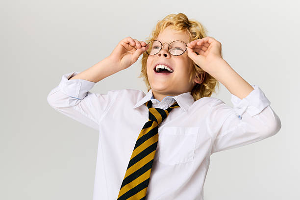 istock Joyful schoolboy in uniform expressing happiness with glasses on in studio setting 2250130806