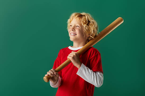Young girl in little league baseball uniform with bat and helmet at home plate