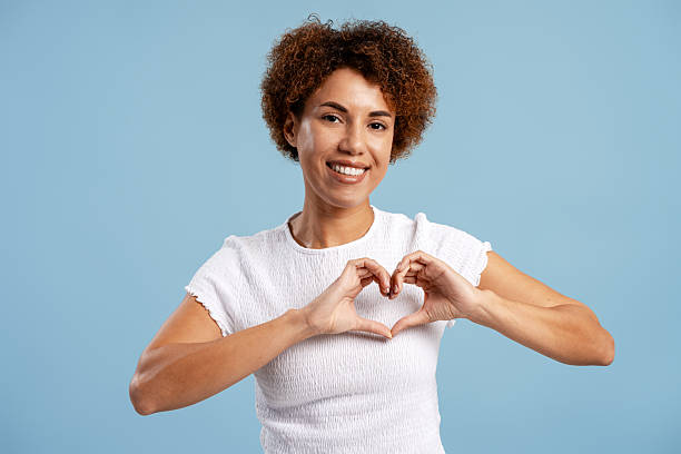 istock Woman smiling and showing heart gesture with both hands, expressing love 2250131631
