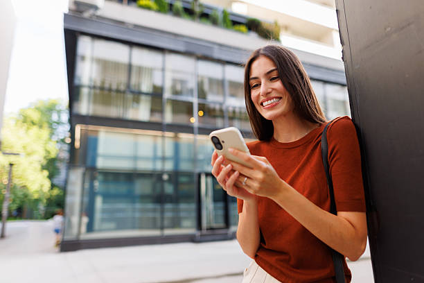 istock Young woman smiling, using smartphone outdoors, enjoying mobile communication in urban environment 2250133226