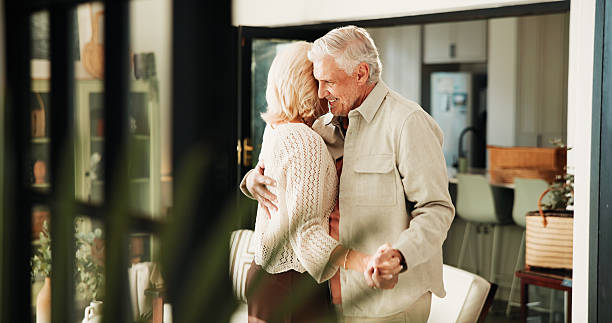 istock Senior couple, love and dance in home for commitment, marriage anniversary and bonding. Romantic music, elderly man and woman holding hands in house for retirement, healthy relationship and smile 2250134347