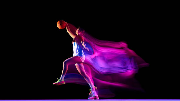 istock Basketball player in jump shot pose surrounded by neon light trails. 2250135780