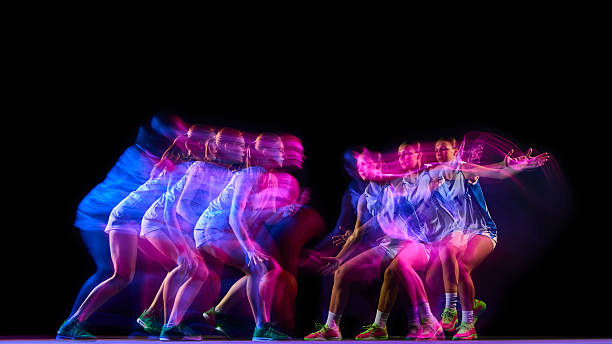 Basketball player in multiple dribble motion with pink and blue lights.
