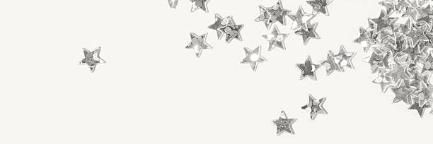 Metallic silver star shaped confetti scattered on a light minimal background with one isolated star