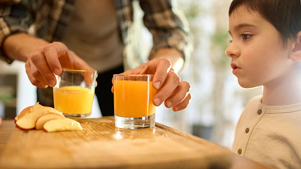 istock Two glasses of citrus juice with father and son comparing drinks in warm soft kitchen light 2250138083