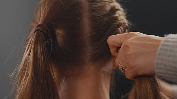 istock Skillful hands effortlessly braiding a young woman's long hair. Rear view. 2250139220