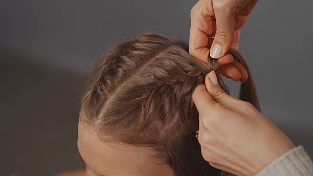 istock Skillful hands effortlessly braiding a young woman's shiny blond hair 2250139238