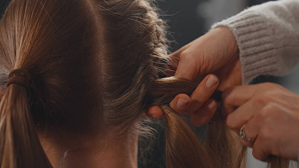 istock Skillful hands effortlessly braiding a young woman's long shiny hair. Rear view. 2250139272