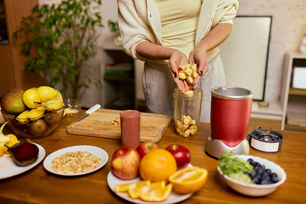 istock Woman adding chopped fruit into blender cup while preparing homemade smoothie 2250139997