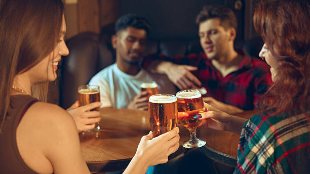istock Friends toasting beer glasses with warm light on pub table 2250142959