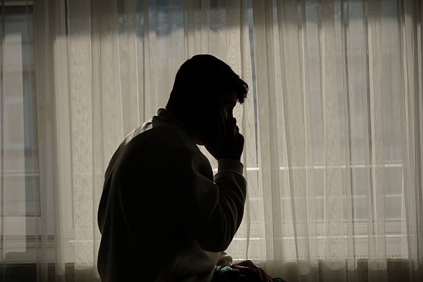 istock The man talking on the phone and texting by the window at sunset. 2250143123