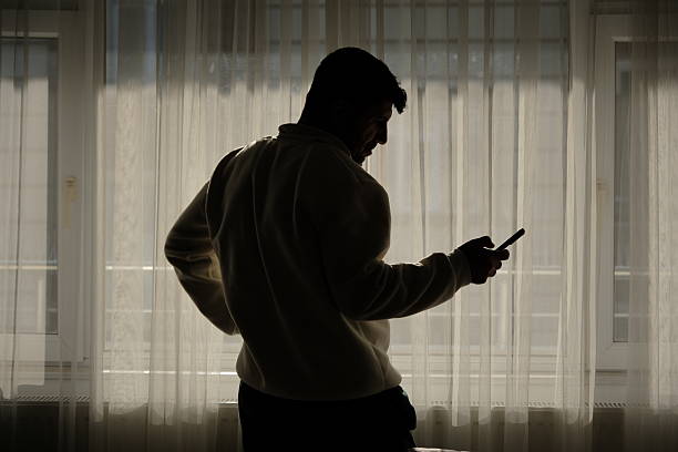 istock The man talking on the phone and texting by the window at sunset. 2250143172