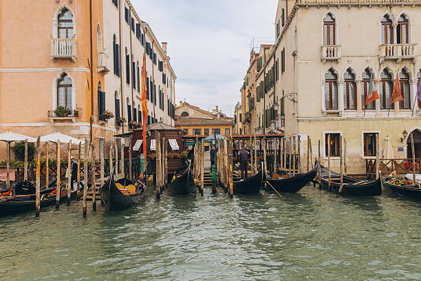 Venice, Italy - October 9, 2025: Traditional Venetian gondolas reflecting in the water, awaiting passengers along a historic canal lined with classic Italian buildings