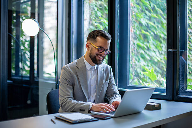 istock Smiling businessman working on laptop in modern office 2250144768
