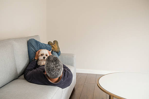 istock A man is laying on a couch with a dog on his lap 2250148740