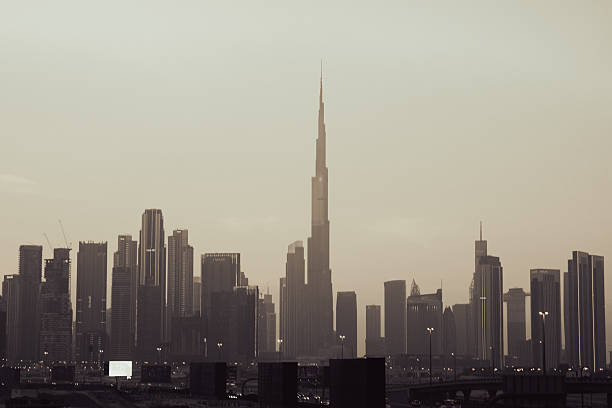 Through desert haze, the tallest tower emerges like a phantom spire, while the city holds its breath in sepia tones, capturing that ethereal moment when dawn hasn't quite decided to break through the morning mist.