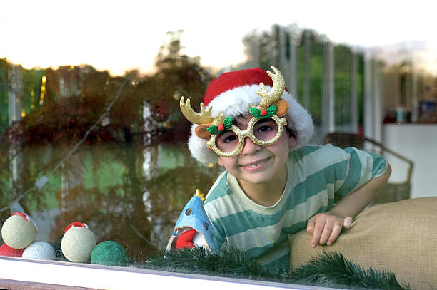 young child looking at the window with christmass sunglases