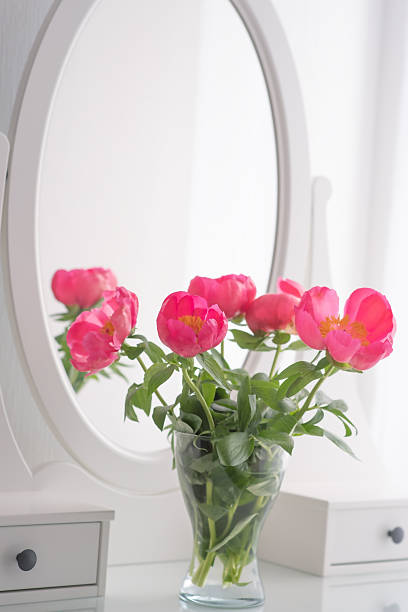 istock Vertical view of an elegant vanity table with a mirror and pink peonies. 2250156306