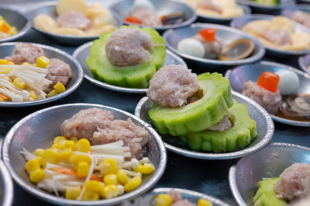 Steamed dim sum including bitter gourd topped with minced meat, minced pork with corn and a variety of other dim sum on the serving plates at local restaurant in China Town, Bangkok Thailand.