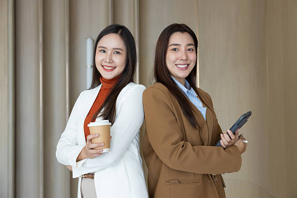 Confident businesswomen standing back to back smiling