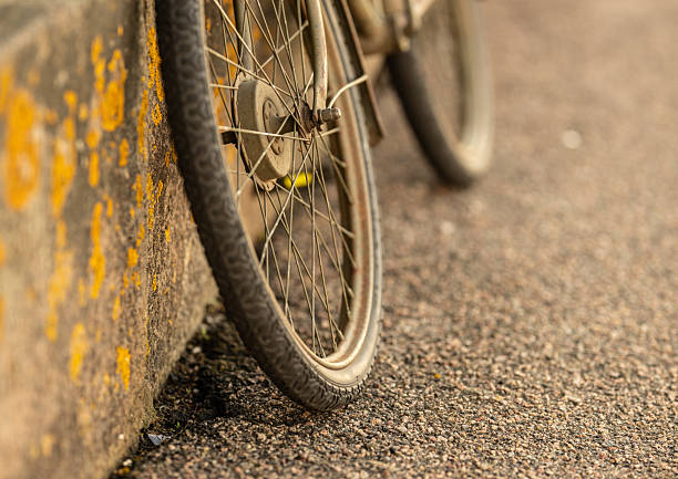 Closeup of worn bicycle wheel beside rough textured pavement surface