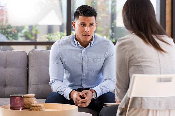 istock Man in light blue button-down shirt talks intently with a therapist in a comfortable office setting. 2250159977