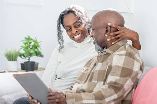 istock Joyful Older Black Couple Sharing a Smile While Looking at Tablet at Home 2250161518
