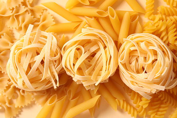 Dry pasta on a yellow background.  The concept of diet and nutrition.