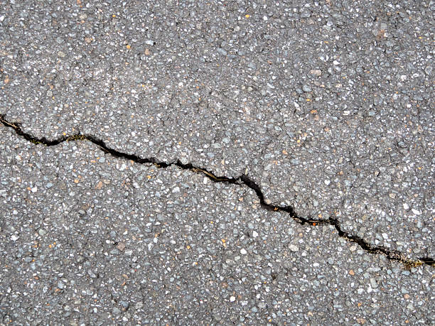 istock Close-up of a diagonal crack in black asphalt 2250163019