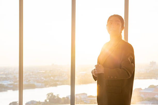 istock Businesswoman using smartphone by office window at sunset 2250166181