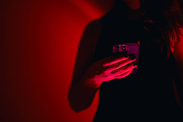 istock Woman holding smartphone in red light at night 2250166391